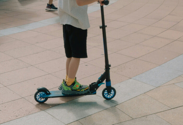 a teenager riding a scooter on the road