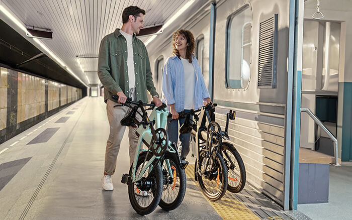 a man and a woman pubsh two engwe p20 lightweight ebike in the station